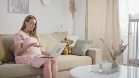 pregnant woman sitting on sofa and using a laptop in online consulation with a doctor 1