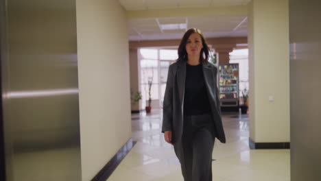 view from inside elevator with doors partially open, woman in business attire seen through the gap, blurred background of office space, modern corporate environment, professional setting, close-up shot