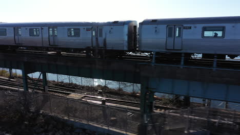 An-aerial-shot-of-an-NYC-subway-on-an-elevated-track-in-Queens,-NY