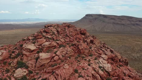 Panning-aerial-shot-of-a-rocky-mountain-peak-with-red-rocks-in-the-middle-of-the-desert