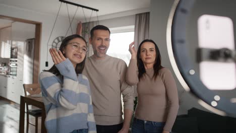 niña adolescente con padres grabando baile para las redes sociales usando teléfono móvil