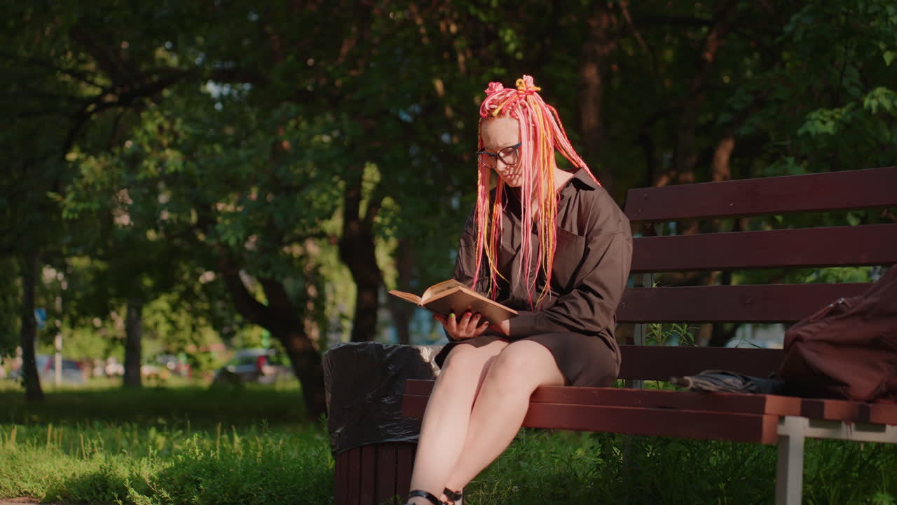 평화롭게 책을 읽는 여성, 야외에서 책에 몰두한 고요한 여성, 나무 아래에서 조용히 독서를 즐기는 평온한 여성, 무성한 녹색 잎 아래에서 문학 속으로 평화롭게 빠져드는 여성