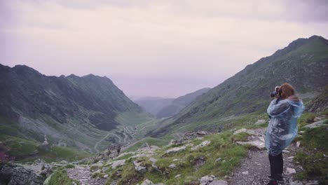a young woman hiker climbs mountains and photographs landscapes on camera. transfagarasan, carpathian mountains in romania