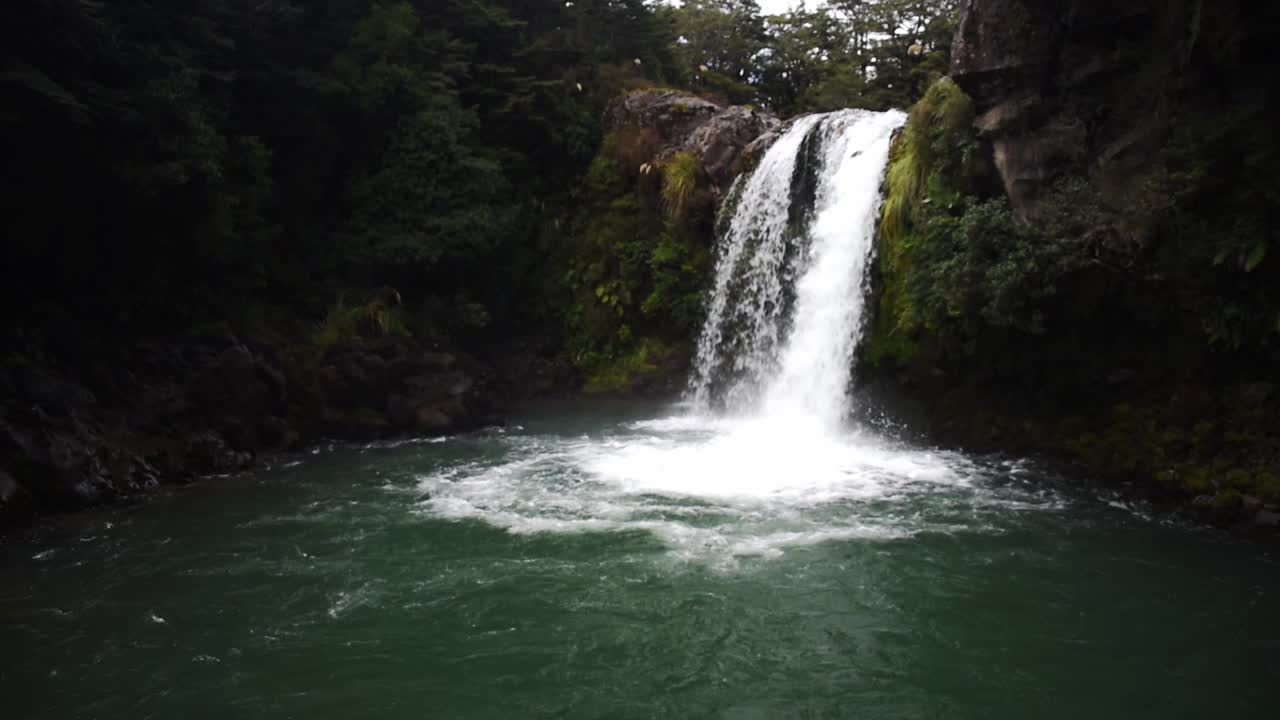 vista panorámica de una cascada que cae en aguas turquesas profundas sobre un acantilado en nueva zelanda