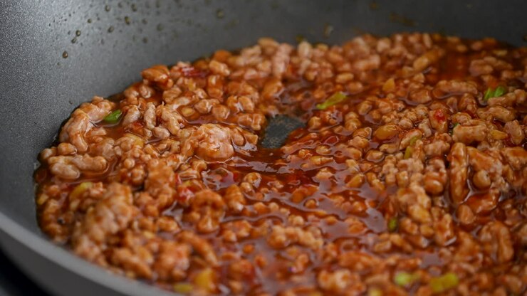 Stir-frying ground pork with hot spicy sauce when cooking mapo tofu cuisine at home.