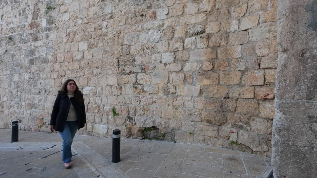 Woman tourist walks towards the Zion Gate in the Old City of Jerusalem.. Slow motion.