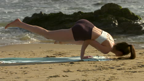 an attractive young woman practicing yoga on a beautiful california beach