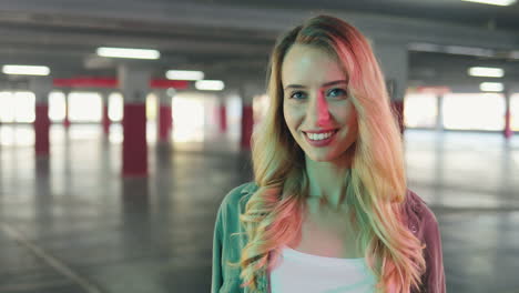 portrait of a young blonde looking to the side, then looks at the camera and smiles cheerfully in an empty parking lot