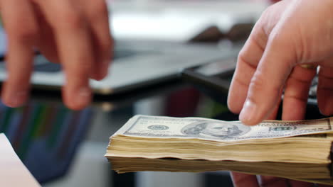 Hand-giving-dollar-bills-on-office-table.-Bank-offers-instant-money-transfer