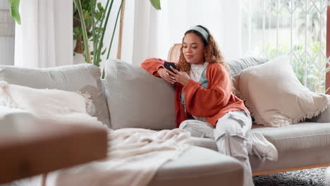 una mujer joven relajándose en un sofá usando un teléfono inteligente