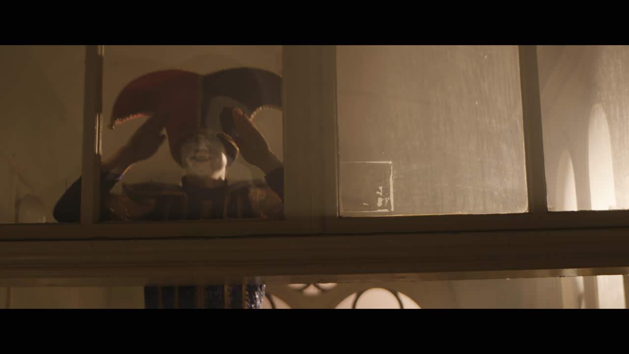 A strange clown on stilts in a dark corridor at night