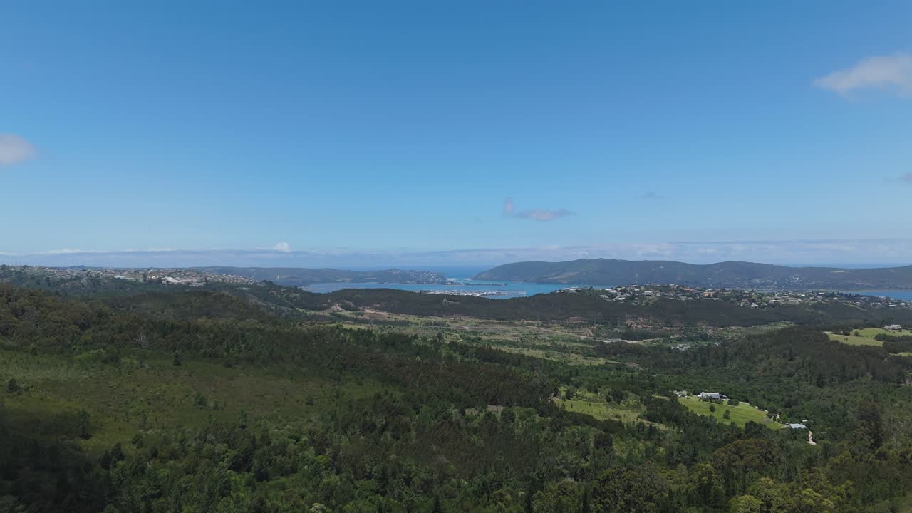 A stunning aerial drone shot showcasing the Knysna Heads, serene lagoon waters, and lush green forests in South Africa's Garden Route, capturing breathtaking natural beauty and tranquil scenery.
