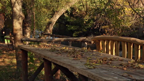 Wooden-table-by-river-in-garden-bathed-in-autumnal-colors