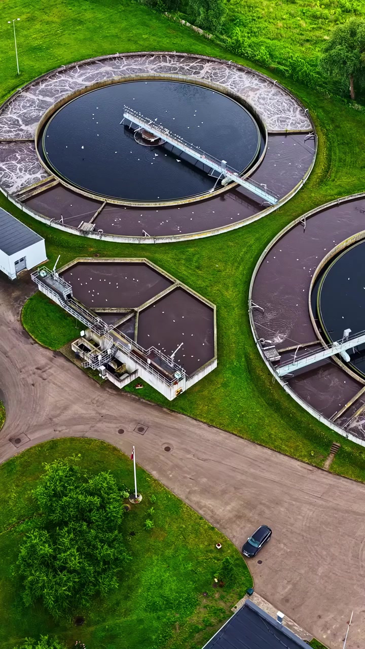 A Wastewater Treatment Plant With Large Circular Tanks and Surrounding Service Roads Used For Water Purification and Environmental Management - Aerial Drone Shot