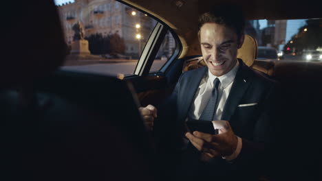 hombre de negocios emocionado regocijándose de buenas noticias en un teléfono inteligente en un coche de lujo.
