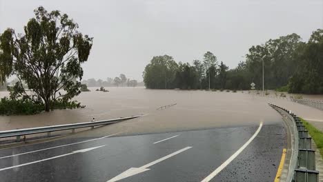 queensland, nsw, australia, february floods - a deserted suburban brisbane road curves down and disappears into flood waters, as heavy rain continues to fall