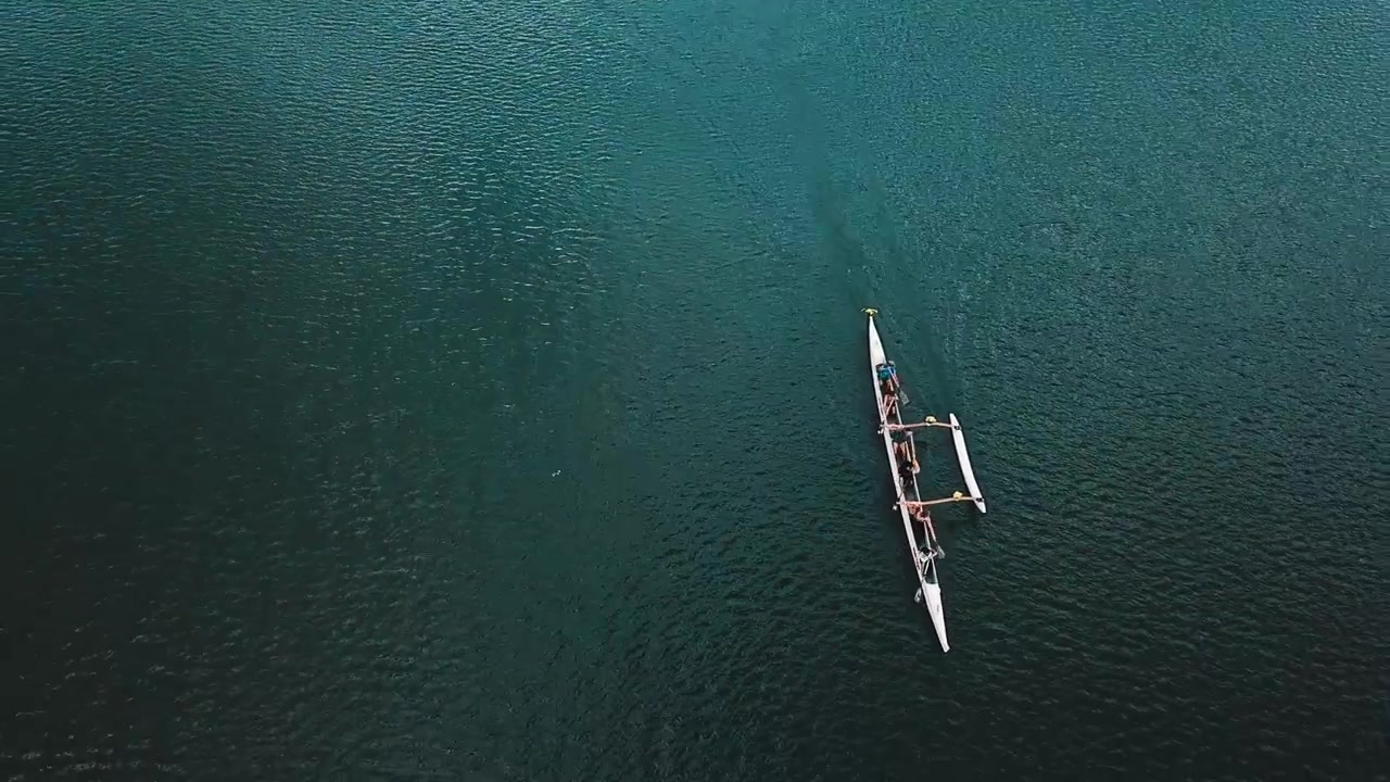 Aerial tracking view above rowing sports team training together in turquoise lake