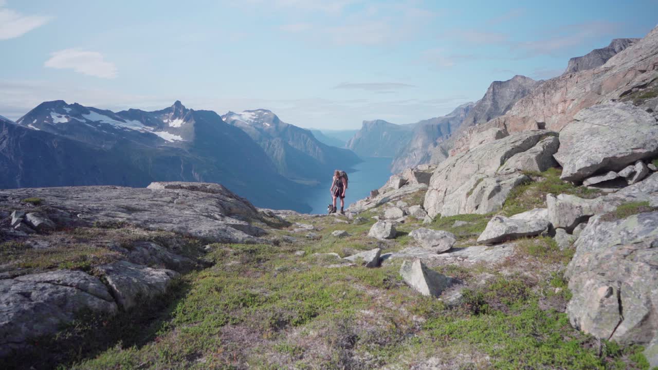 excursionista con perro camina al borde del acantilado después de admirar la vista panorámica en katthammaren, noruega