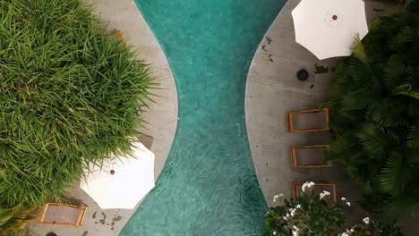 top down bird's eye view drone shot revealing an hourglass shaped pool at a luxurious resort located in bali, indonesia