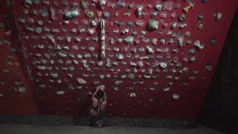 woman rock climbing on a red climbing wall