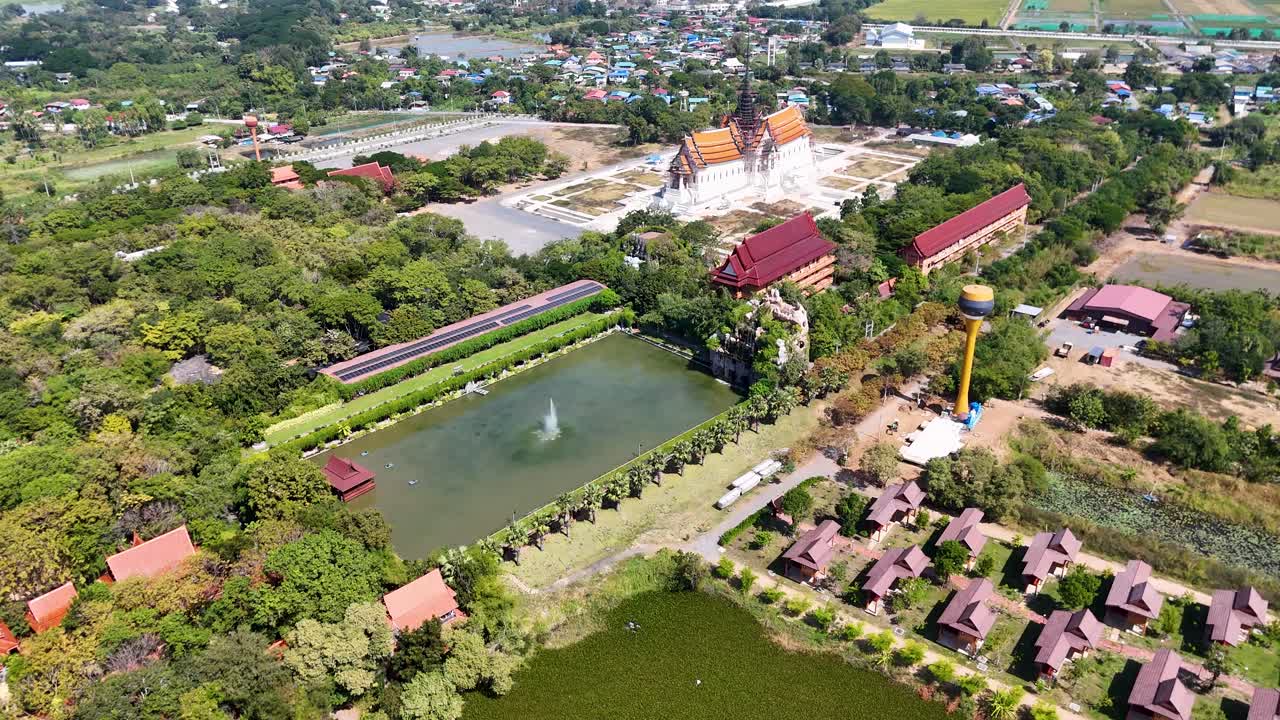 Une vue aérienne en plongée, prise par un drone, révèle un complexe de temples bouddhistes avec des panneaux solaires et des bassins de jardin