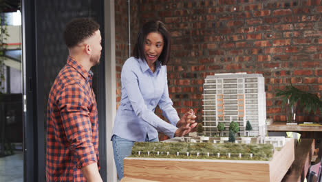 diverse male and female architect discussing architectural model, slow motion