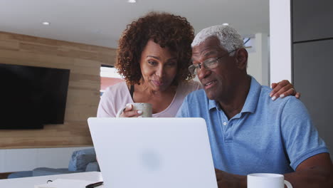 una pareja afroamericana de alto nivel que usa una computadora portátil para verificar las finanzas en casa