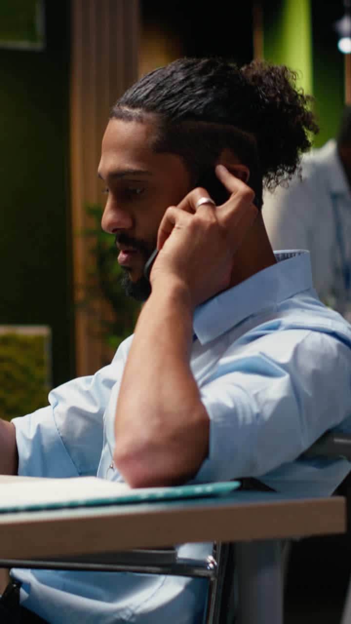 Vertical Video Middle Eastern wheelchair user engaged in phone call during office work