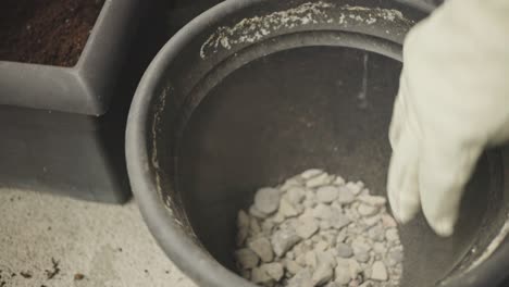 putting stones and soil into planting pot. closeup