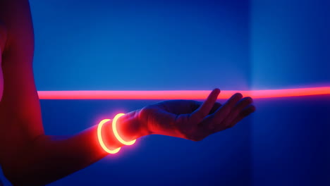 arm with glowing bracelets in neon blue and red light