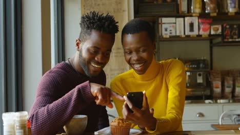 Couple-using-mobile-phone-in-cafe-4k