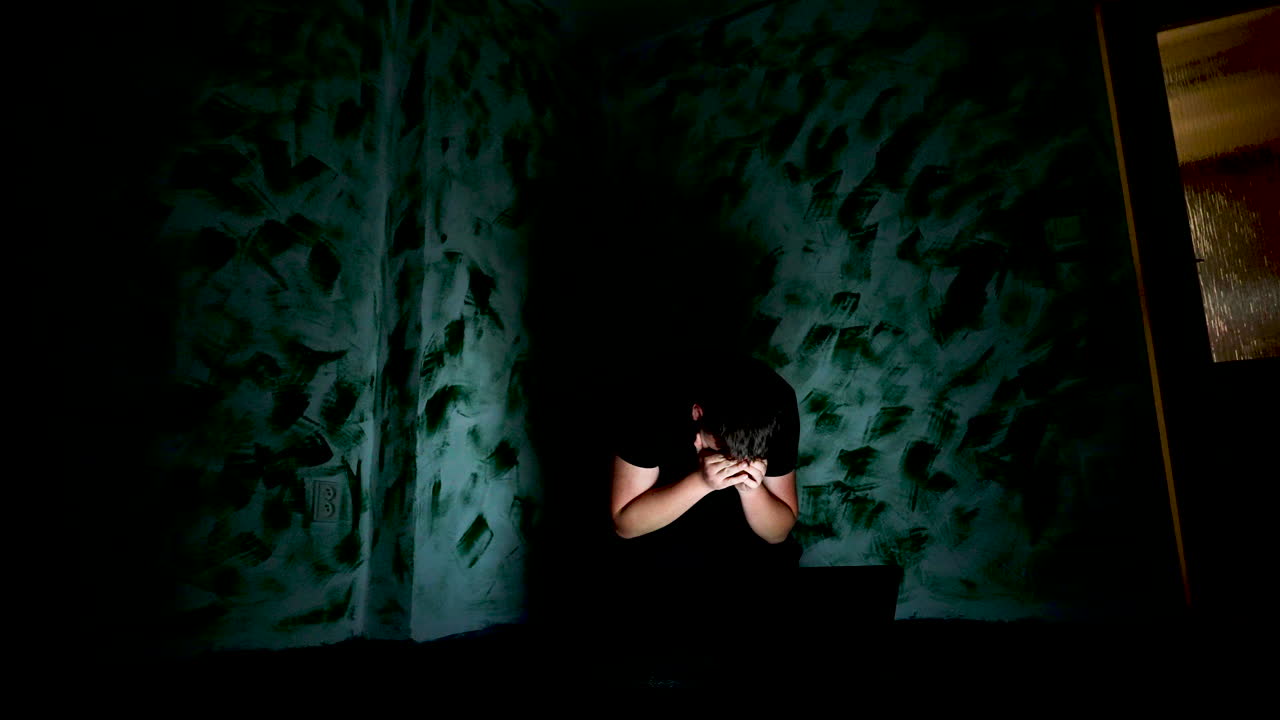 우울한 청년은 온라인 증오 메시지, 사이버 괴롭힘 개념을 읽은 후 얼굴을 가린다