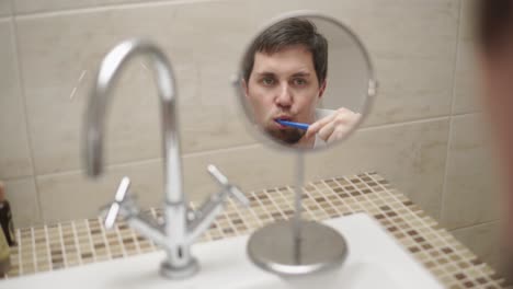 hombre cepillándose los dientes en el baño
