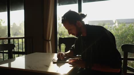 man writing or drawing with a stylus in natural light