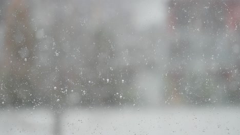 Wassertropfen-Haften-An-Der-Fensterscheibe,-Während-Draußen-Ein-Schneesturm-Tobt