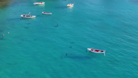 Dolly-Cinematográfico-De-Drones-Inclinado-Hacia-Barcos-De-Pesca-Anclados-En-Aguas-Cristalinas-Del-Caribe-De-Boca-Sami,-Curacao