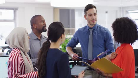 Group-of-diverse-business-people-holding-documents-and-talking-in-office,-slow-motion