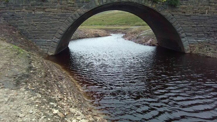 Piccolo ponte nelle brughiere dello Yorkshire con un fiume color torba che lo attraversa