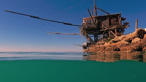 Geteilte-Unterwasseransicht-Von-Trabocco-Oder-Trabucco-Am-Strand-Von-Punta-Pene-An-Der-Costa-Dei-Trabocchi-Bei-Sonnenuntergang,-Abruzzen-In-Italien