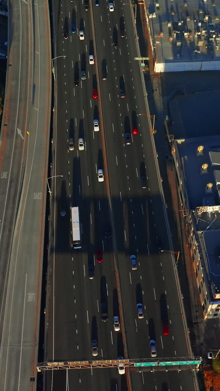 Flight above the overhead road with lots of cars moving by. Los Angeles roofs with helicopters on. Aerial view. Vertical video