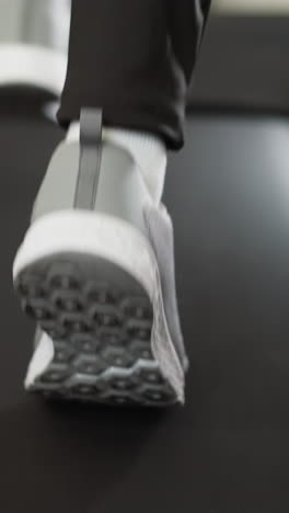 mujer corre en cinta de correr en casa de cerca. mujer atlética en zapatos deportivos corre haciendo ejercicio en la máquina de entrenamiento en casa en cámara lenta. fitness doméstico