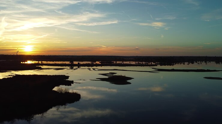 Vasto pântano e pôr do sol dourado, vista aérea ascendente de drone.