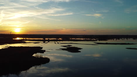 Endless-marshland-and-golden-sunset,-aerial-drone-ascend-view