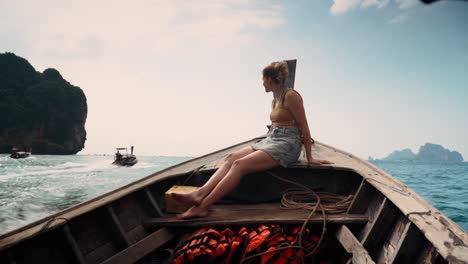 young and adventurous traveler enjoying the scenic views on the bow of traditional a long tail boat to west railay beach