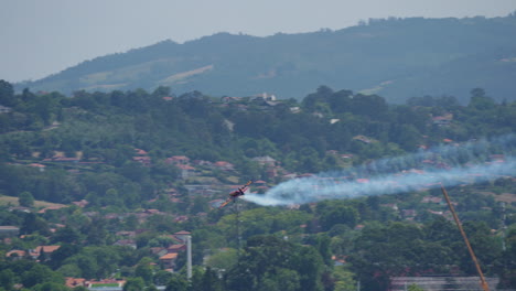small airplane with long vertical smoke trail performing stunt by flying straight up into clear sky