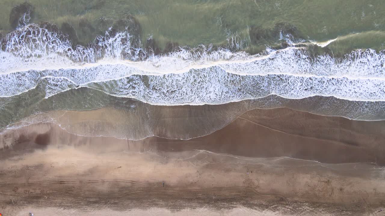Static top down drone shot of a beach in Caril&oacute;, Argentina with waves crashing on the shore