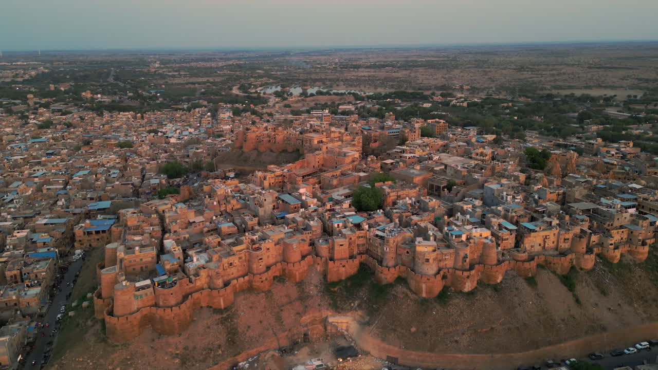 la toma de drones en órbita del fuerte de jaisalmer, rodeado de casas y caminos al atardecer. la cálida luz de la tarde da una vista impresionante del antiguo fuerte y sus alrededores rajasthan india