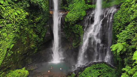 turistas tomando fotos en la base de la cascada de sekumpul, bali