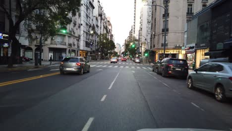 pov driving window's seat view of buenos aires city, santa fe avenue at sunset, argentine illuminated downtown in recoleta neighborhood