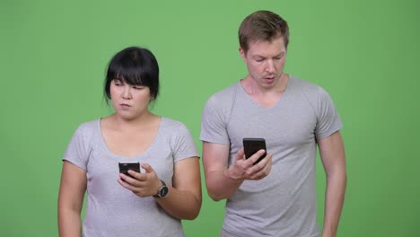 young serious multi-ethnic couple using phone and thinking together